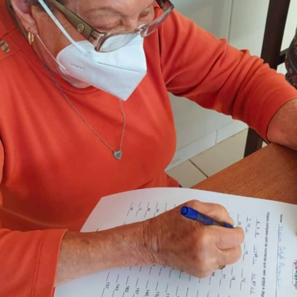 Residente do Residencial Geriátrico Recanto Verde preenchendo ficha de exercício terapêutico.