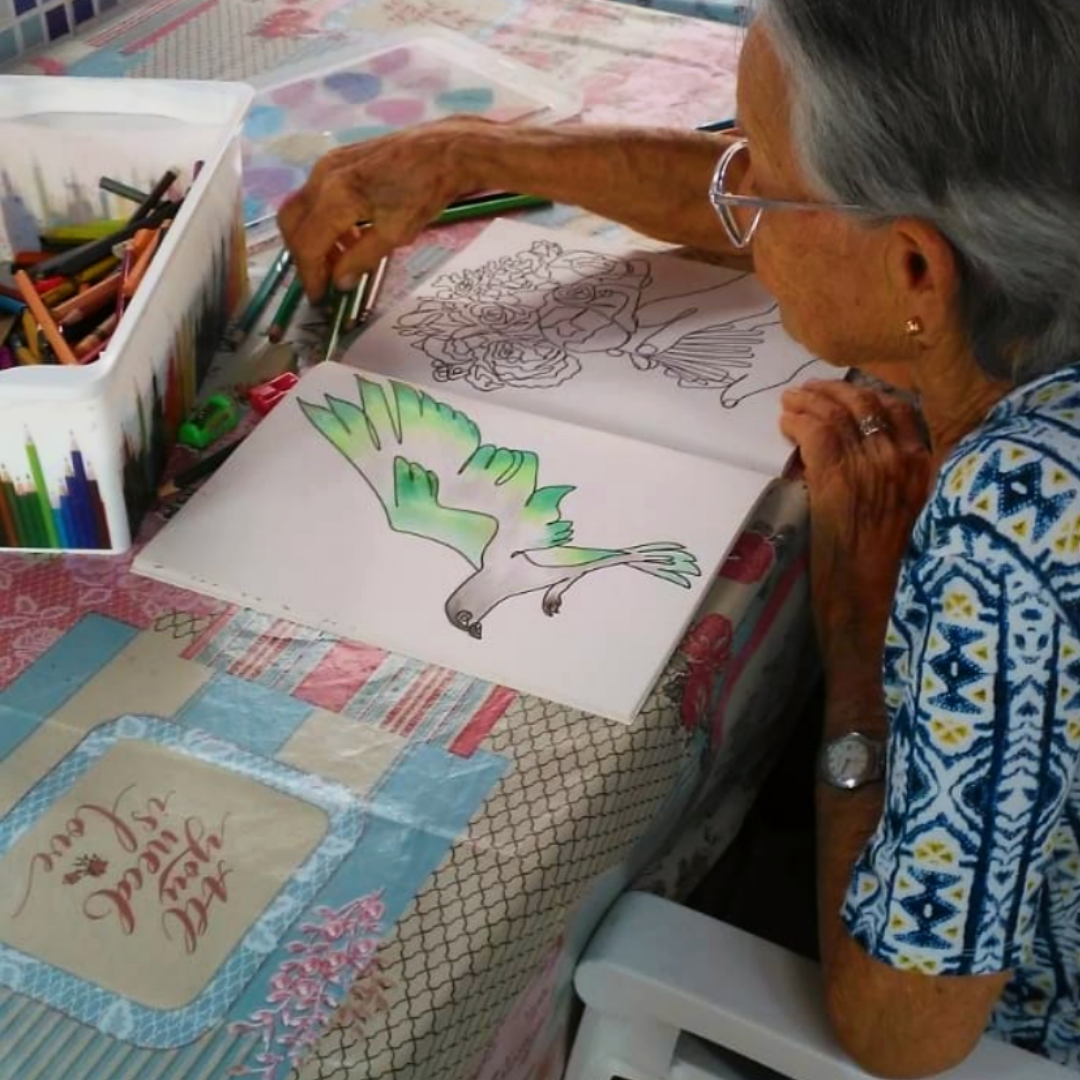 Senhora idosa colorindo desenho de um pássaro