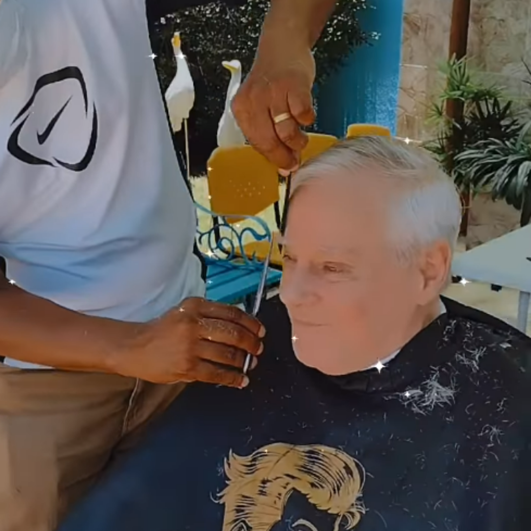 Profissional cortando o cabelo de senhor idoso no Residencial Longévité