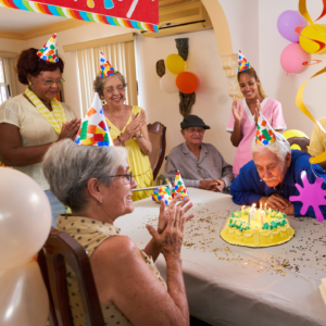 Grupo de pessoas comemorando em volta de mesa com bolo
