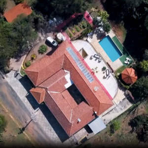 Imagem aérea da Estância das Flores, destacando o prédio principal e a área externa com piscina.