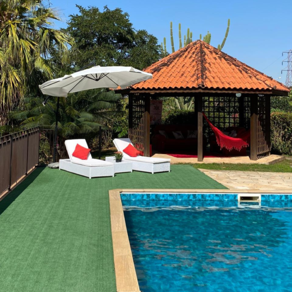 Gazebo ao lado da piscina na Estância das Flores, equipado com espreguiçadeiras e rede.