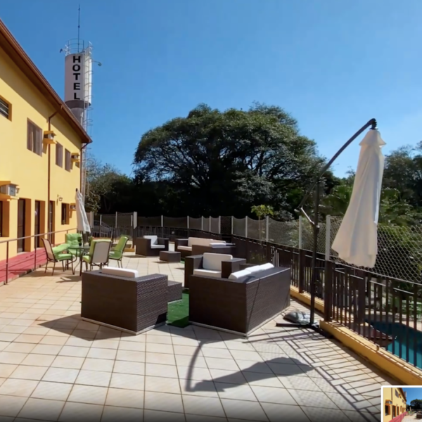 Varanda da Estância das Flores com cadeiras e guarda-sol.