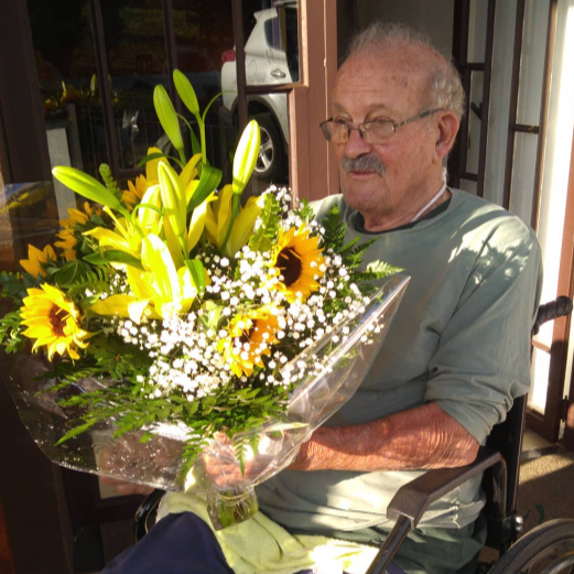 Residente segurando um buquê de flores com girassóis na Estância das Flores.