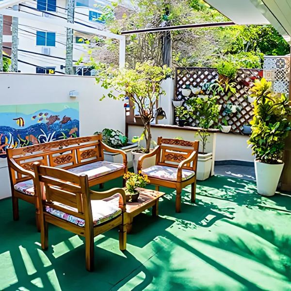 Área externa cuidadosamente planejada, com bancos de madeira, plantas ornamentais e um ambiente agradável para socialização e momentos de lazer ao ar livre.