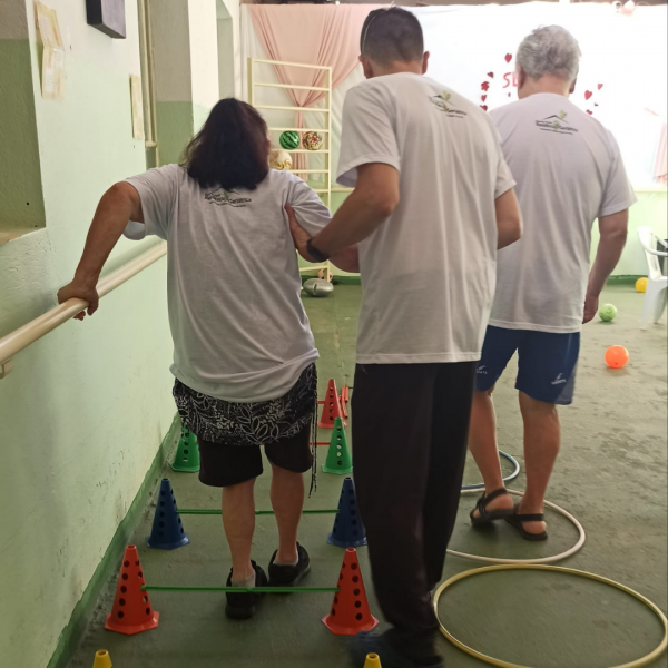Três residentes do Residencial Geriátrico Recanto Verde fazendo fisioterapia com o apoio de um profissional
