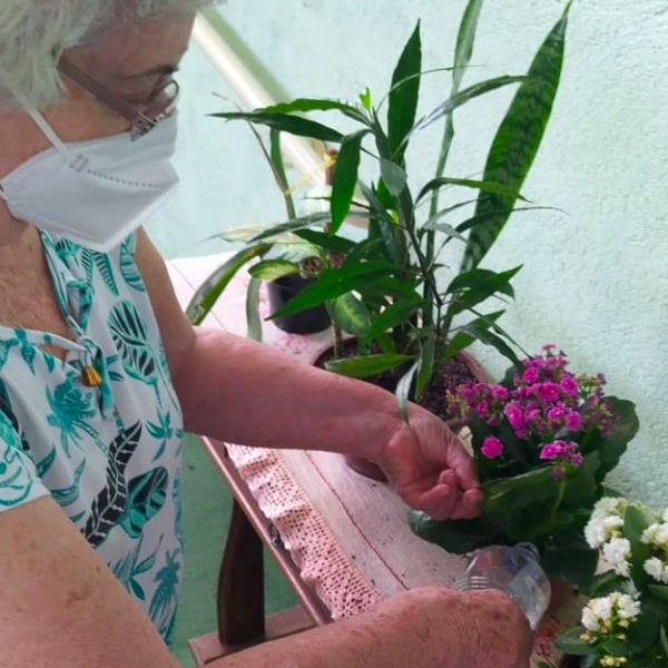 Senhora residente do Residencial Geriátrico Recanto Verde cuidando de flores